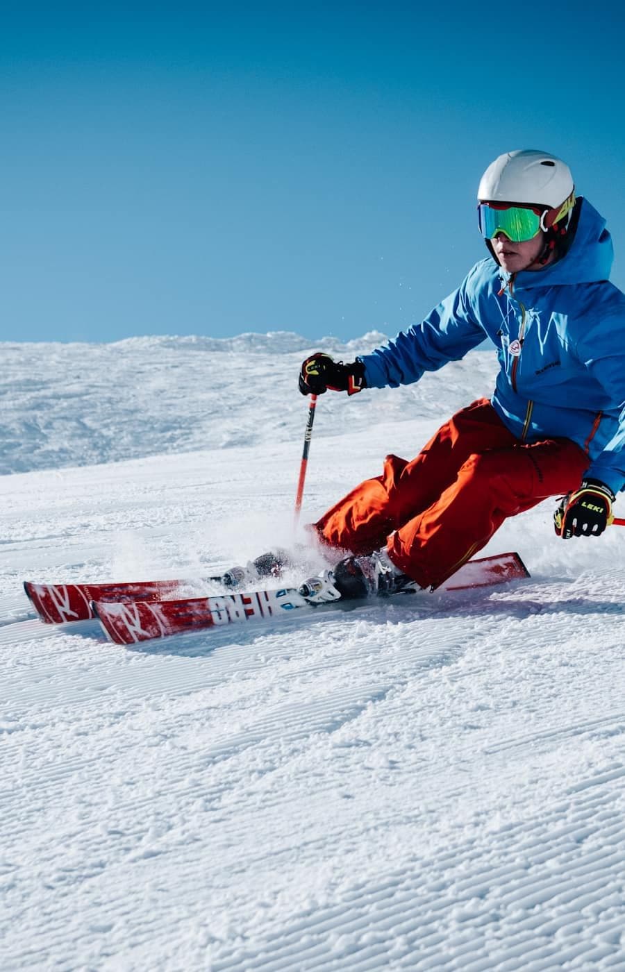 A skier in a blue jacket carves a turn on a sunlit slope.